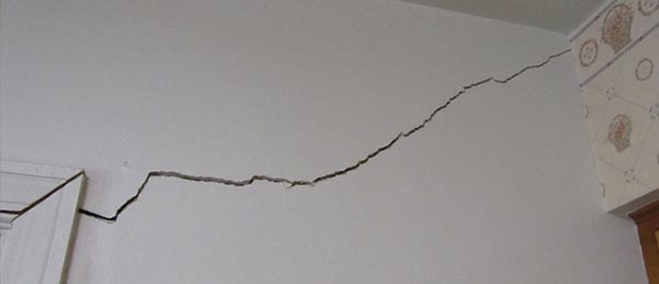 A large crack inside the foundation of a home spanning from the door jam to the corner of the room