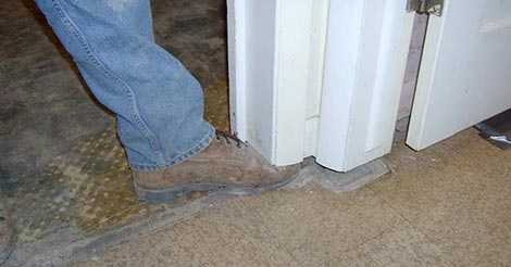 A gap between the floor and a wall where the gap is so big a technician can fit his foot between the two